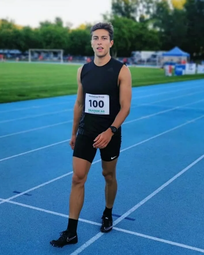 Marius Grek en tenue de compétition, dossard 100, debout sur une piste d'athlétisme bleue lors du Schachencup de Brugg, en Suisse
